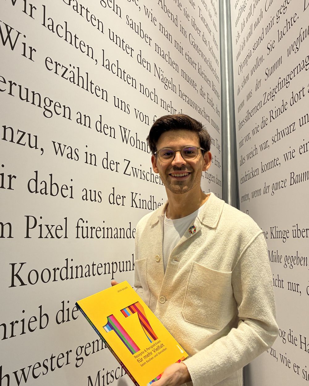 Jean Bauer mit dem Buch vor einer Wand voller Text