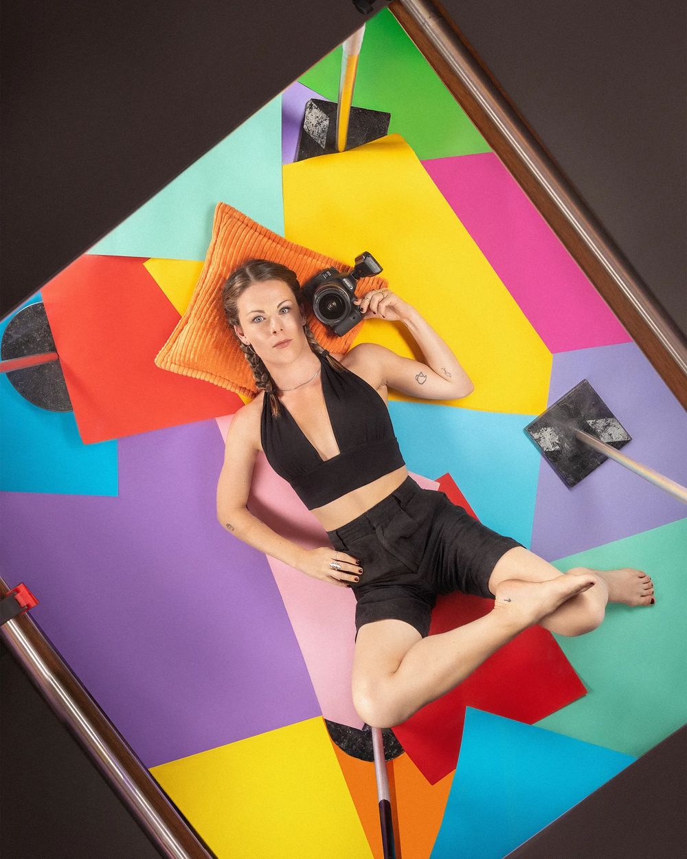 Fotografin Emily Wild mit Kamera auf buntem Papierhintergrund